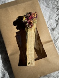 a wooden stick with a flower in it sitting on top of a brown paper bag