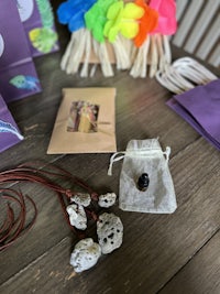 a bag with a necklace, earrings, and other items on a table