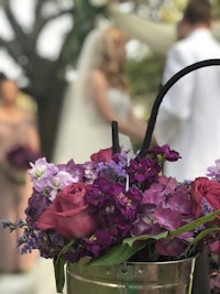 purple flowers in a bucket in front of a bride and groom